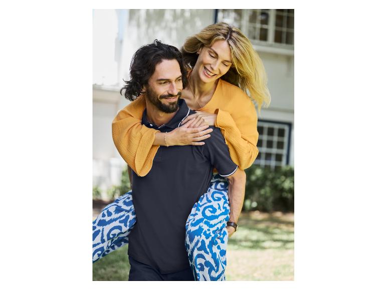 Gelukkig stel; zij draagt een oranje jurk en een blauwe, geprinte broek, hij een zwart polo shirt.
