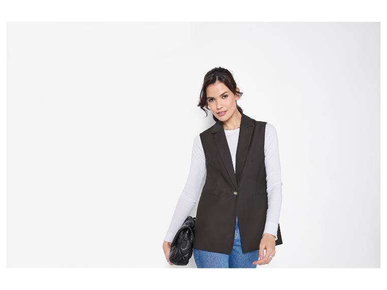 Vrouw met zwart gilet, wit shirt, jeans en zwarte tas.