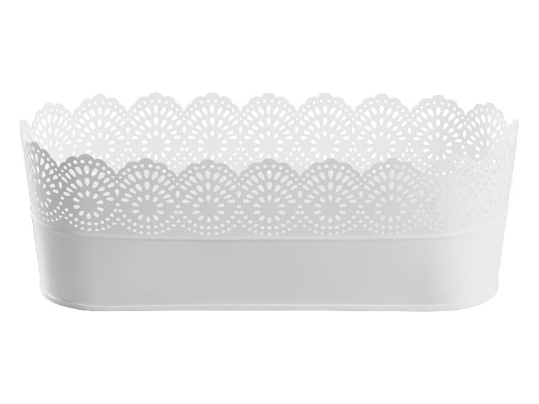 Een witte, ovale plantenbak met een decoratief, geperforeerd randje.