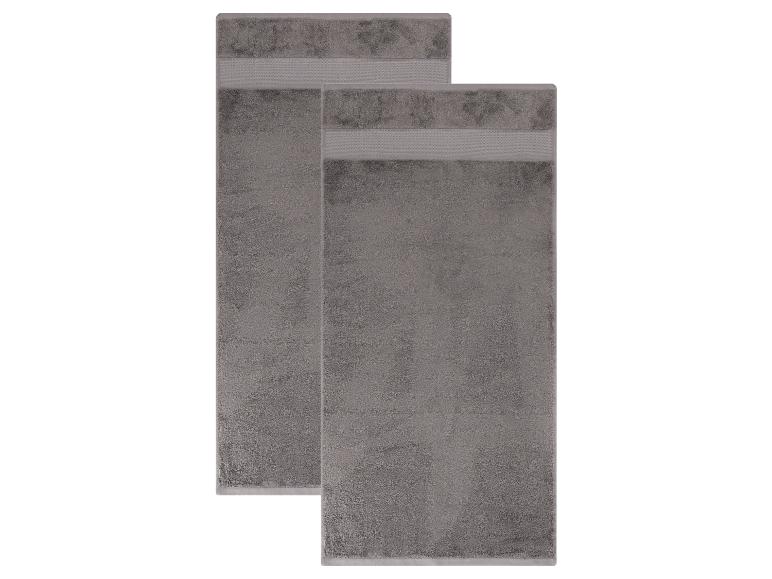 Twee grijze badhanddoeken met decoratieve banden