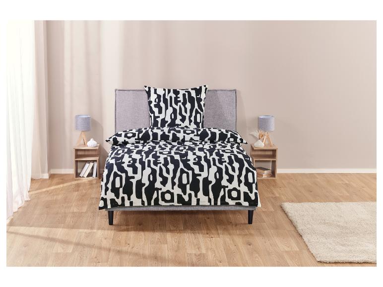 Een bed met een zwarte en witte geometrische dekbedovertrek.