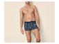 Man in boxershort met patroon tegen een effen achtergrond.