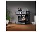 Zwart espressomachine met koffiebonen en een glas espresso op een houten tafel.