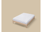 Wit matras op een houten bedframe tegen een beige achtergrond.