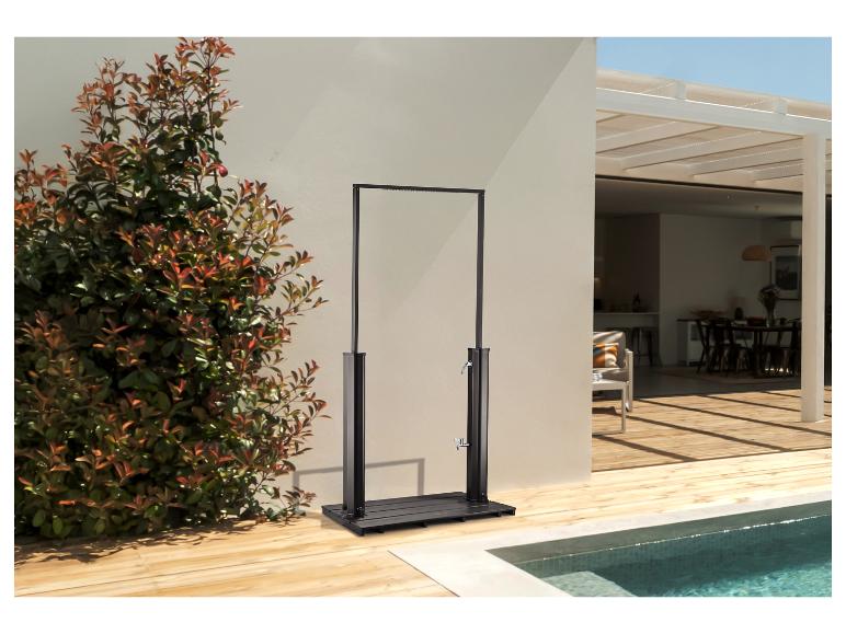 Buitendouche met zwart frame en houten basis naast een zwembad en groene planten.