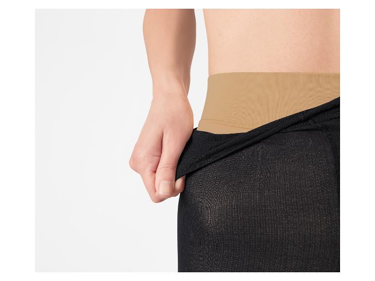 Persoon trekt zwarte legging aan met een beige tailleband.