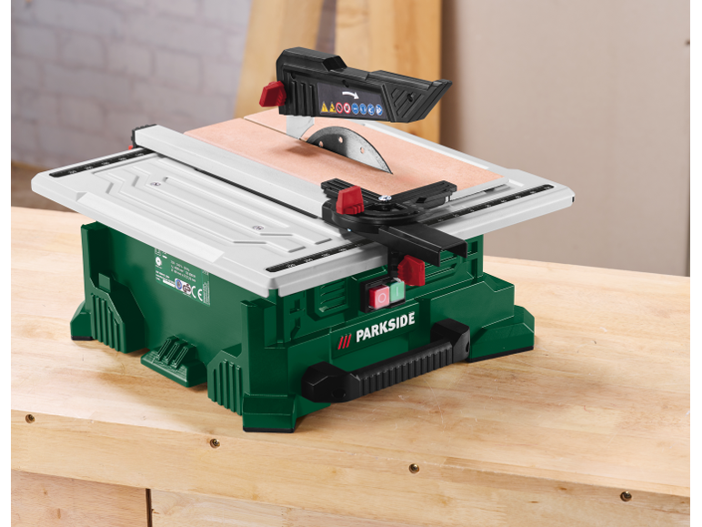 Groene tafelzaag met wit werkoppervlak op een houten tafel.