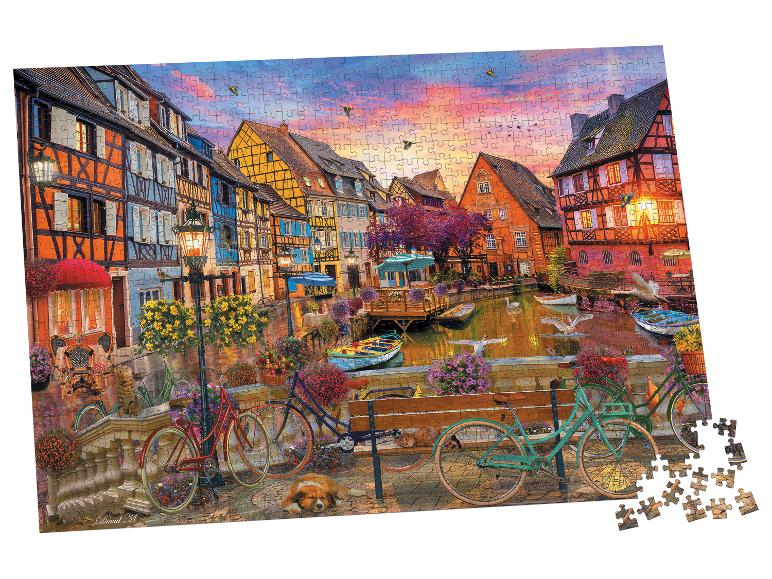 Puzzel met een pittoreske kanaalstad bij zonsondergang, kleurrijke huizen en fietsen.