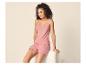 Lachende vrouw in roze tweedelige gerimpelde pyjama, zittend op een bank.