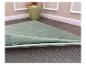 Lichtgroen vloerkleed met antislip onderkant, liggend op een houten vloer.