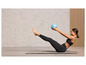 Een vrouw doet buikspieroefeningen met een blauwe fitnessbal op een yogamat.