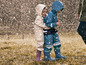 Twee kinderen in regenkleding en laarzen spelen in de regen.