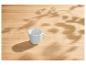 Witte mok op een lichte houten tafel met bladerschaduwen