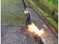 Thermische onkruidbrander in actie op een bemost pad.
