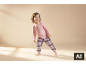 Lachend meisje in roze pyjama met croissantprint en geruite broek.