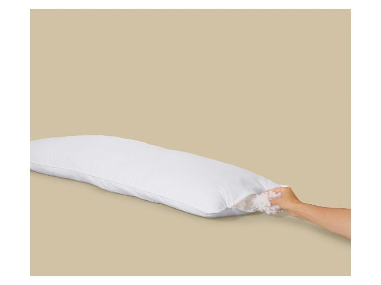 Wit rechthoekig kussen met open rits en een hand die vulling toevoegt.