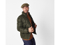 Man met platte pet, groen pufferjack en bruine trui.