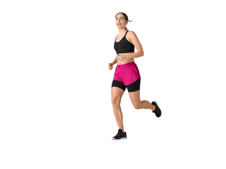 Een vrouw rent in een zwarte sportbeha en roze shorts.