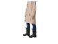Persoon in beige regenjas, jeans en zwarte regenlaarzen.