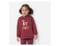 Een peutermeisje lacht terwijl ze een bordeauxrood sweatshirt met een hertenapplicatie en bordeauxrode leggings draagt.