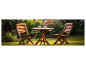 Houten tafel en stoelen in een bloeiende tuin.