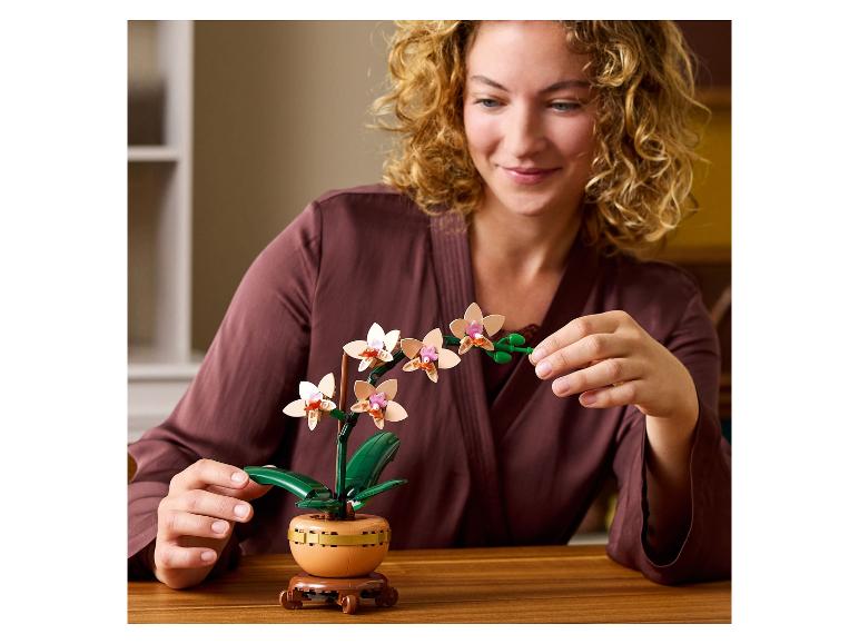 Lachende vrouw met een bouwbare orchidee op een houten tafel.
