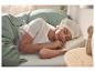 Vrouw slaapt in bed met wit T-shirt en haarkapje, onder groen beddengoed.
