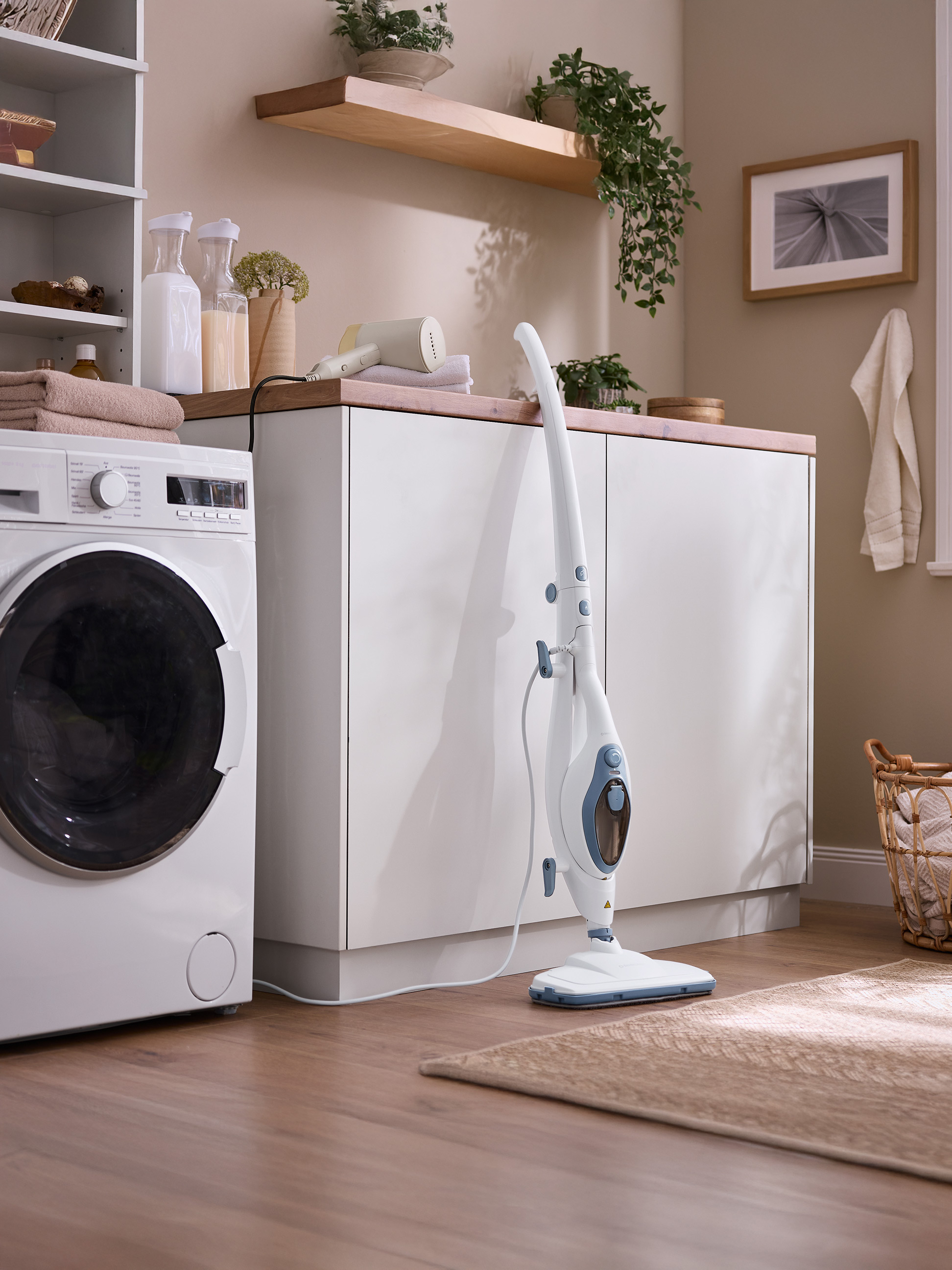 Wasruimte met wasmachine, stoommop en opbergoplossingen.