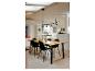 Eetkamer met houten tafel, zwarte stoelen en moderne hanglamp.