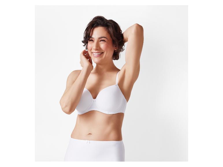 Een vrouw lacht terwijl ze een witte bh en een hoge taille ondergoed draagt.