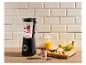 Zwarte blender met bessen en yoghurt, fruit en granola op een houten tafel.