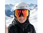 Persoon met witte skihelm en reflecterende skibril, zwarte ski-jas, besneeuwde bergen op de achtergrond.