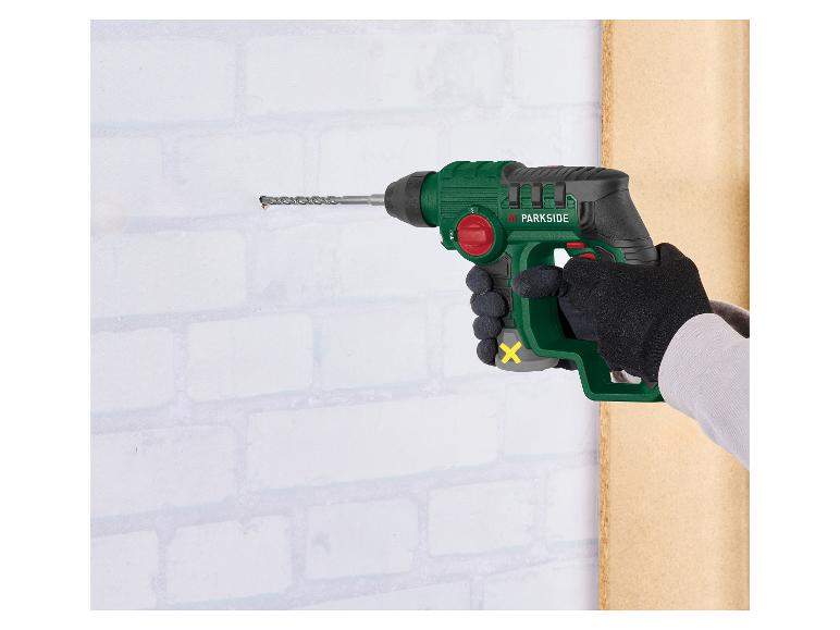 Handboormachine boort een gat in een witte bakstenen muur.