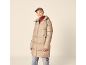 Vrouw in beige pufferjack, rode coltrui en pet