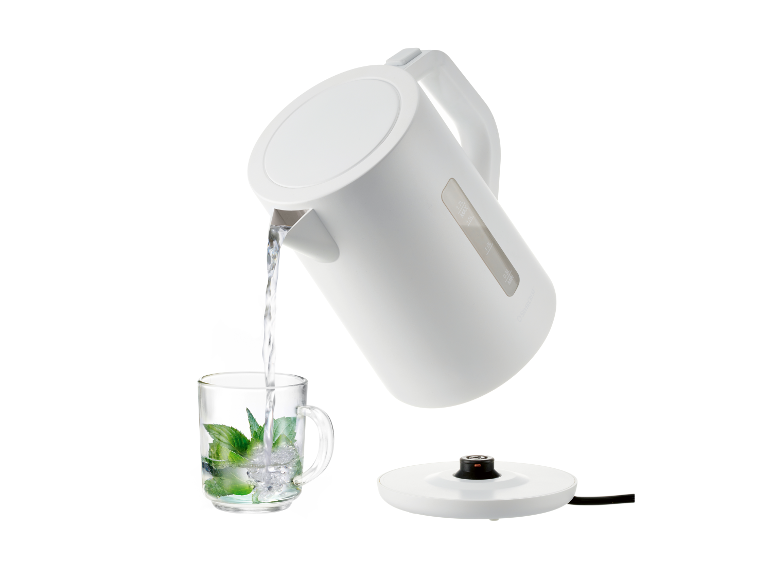 Een wit waterkoker giet water in een mok met munt.