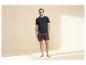 Man in donkerblauw T-shirt en rood geruite shorts.