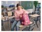 Een meisje zit op een schoolbank en opent haar roze CRELANDO® schoolrugzak.