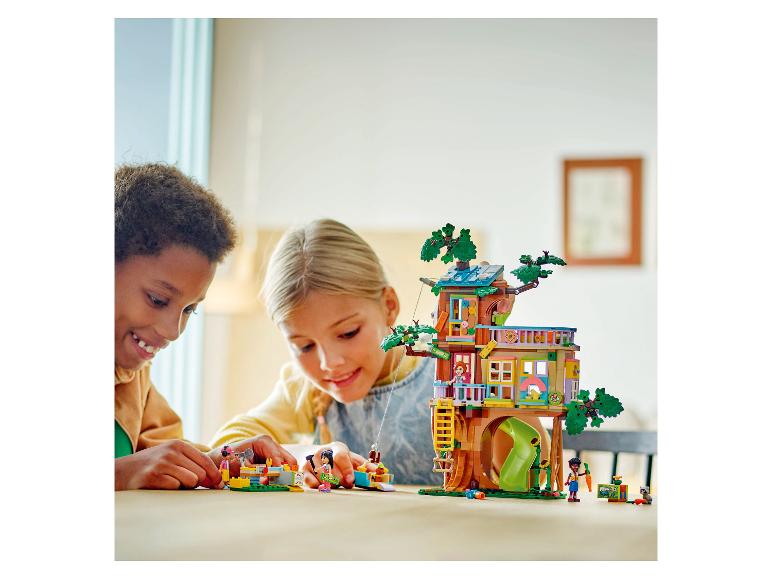 Twee kinderen spelen met een LEGO Friends set, een kleurrijke boomhut.
