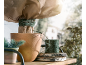 Terracotta pot met plant gewikkeld in beschermende stof en groen touw op een houten plank.