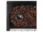 Koffiebonen in het reservoir van een koffiezetapparaat met maalgraadknop.
