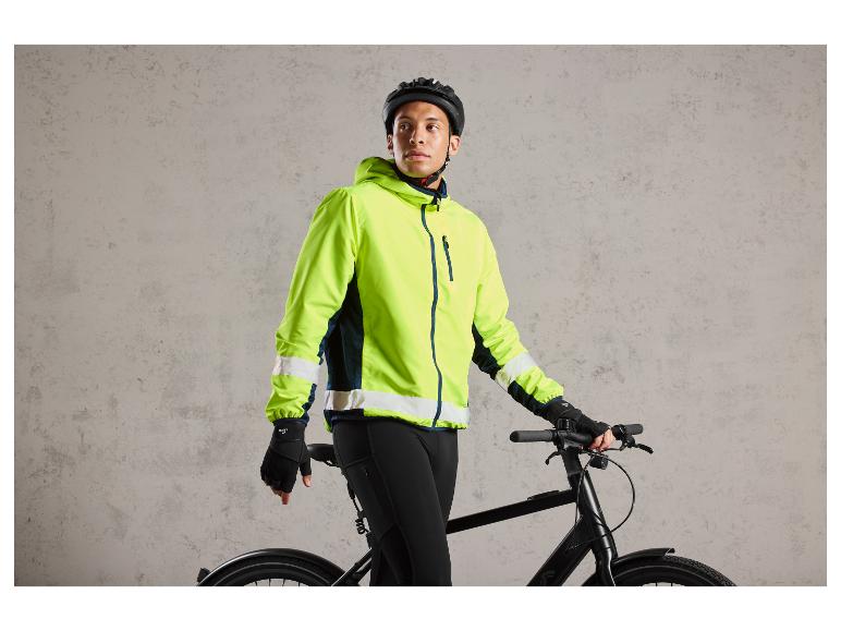 Een man in een felgele fietsjas en zwarte handschoenen staat naast een zwarte fiets.