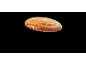 Een goudbruine amandelkoek met een gekartelde rand tegen een zwarte achtergrond.