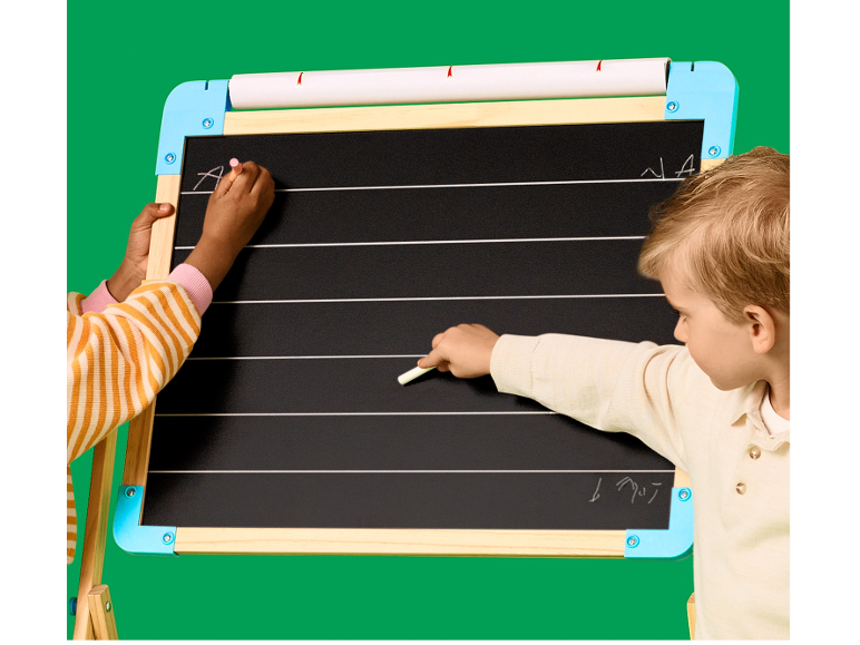 Twee kinderen schrijven met krijt op een schoolbord met lijnen om te leren schrijven.