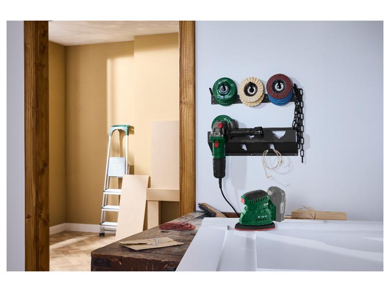 Een werkplaatsscène met een slijpmachine en schuurmachine op een werkbank, met schuurschijven aan de muur.