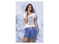 Een vrouw draagt een wit T-shirt met een blauwe print en blauwe shorts.