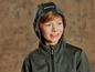 Een jongetje draagt een groene softshell jas met capuchon.