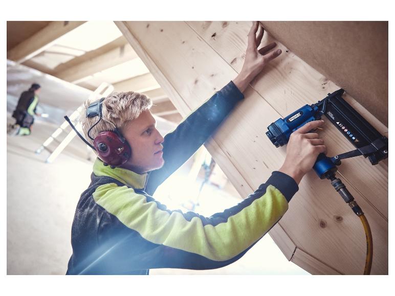 Man gebruikt een LIVARNO® pneumatische tacker/spijkerpistool om houten panelen te bevestigen.