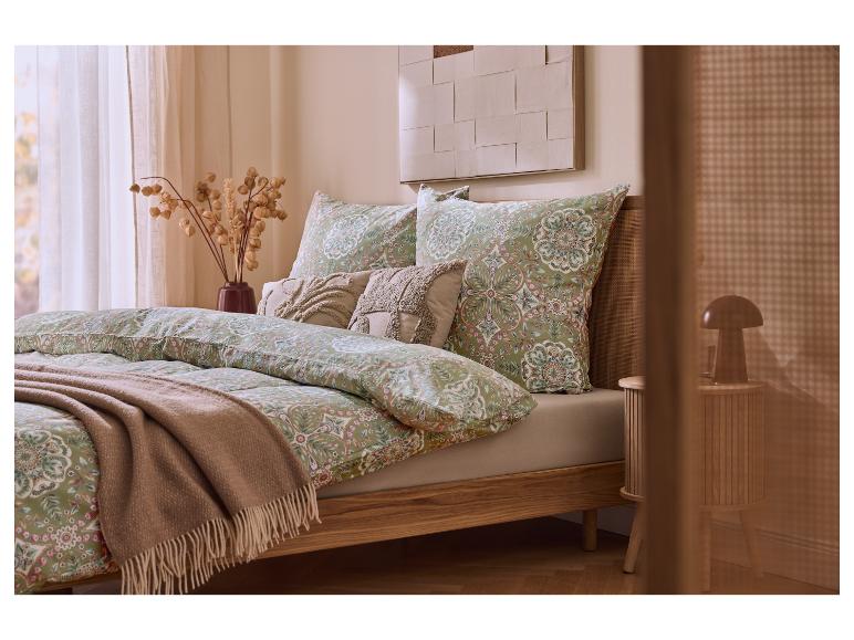 Slaapkamer met bed met houten frame, groen-roze beddengoed met patroon en beige deken.