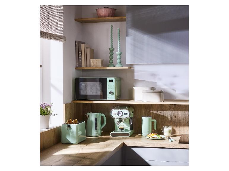 Mintgroene keukenapparatuur: magnetron, broodrooster, waterkoker en espressomachine op een houten aanrecht.