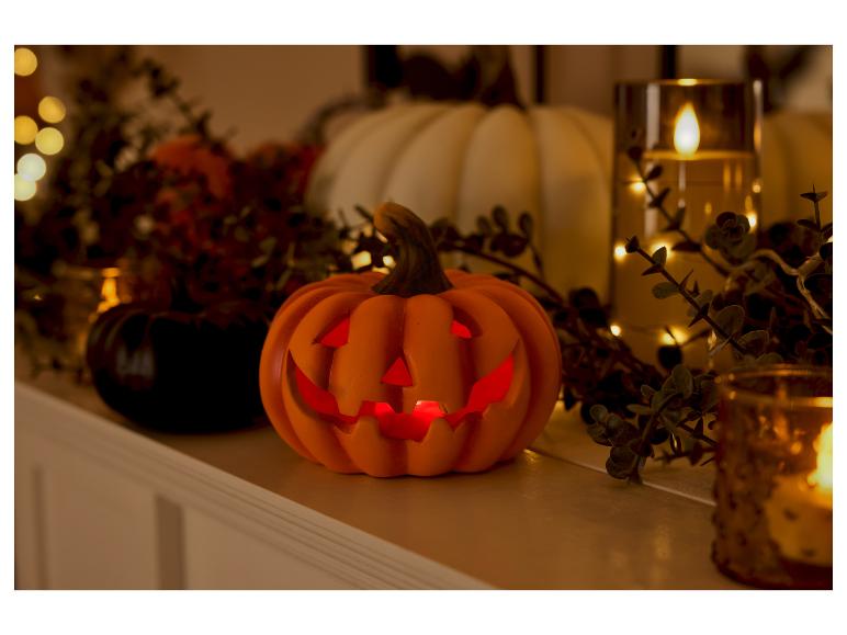 Verlichte oranje LED-Halloweenpompoen op een versierde schouw.